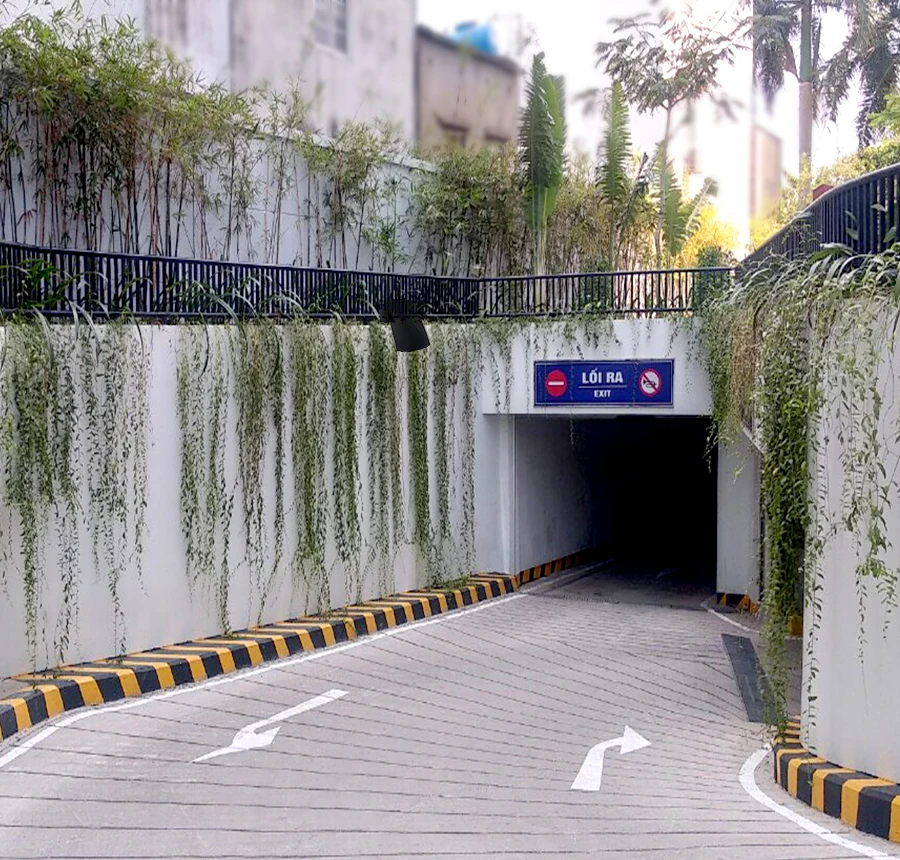 Lối xuống hầm đỗ xe D-Vela, có biển hướng dẫn và dải cây xanh.